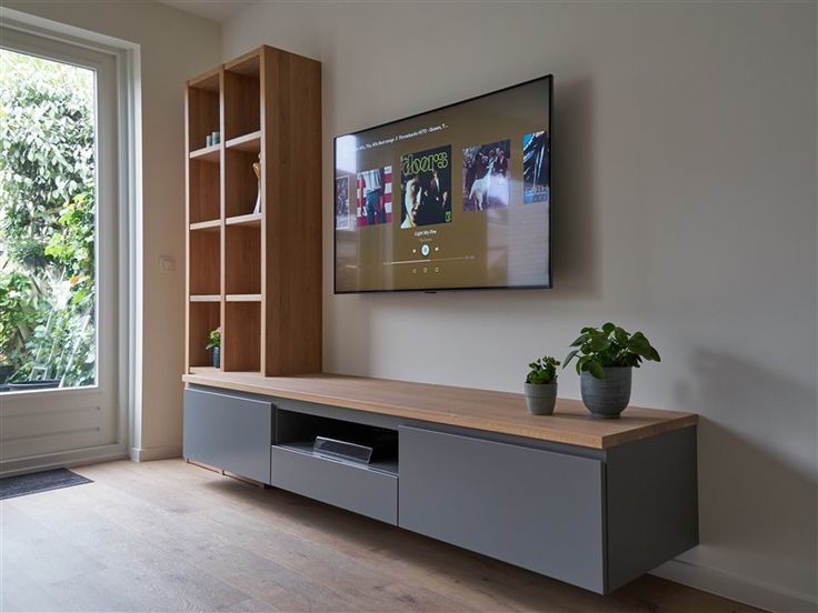 a flat screen tv mounted to the side of a wall next to a wooden shelf