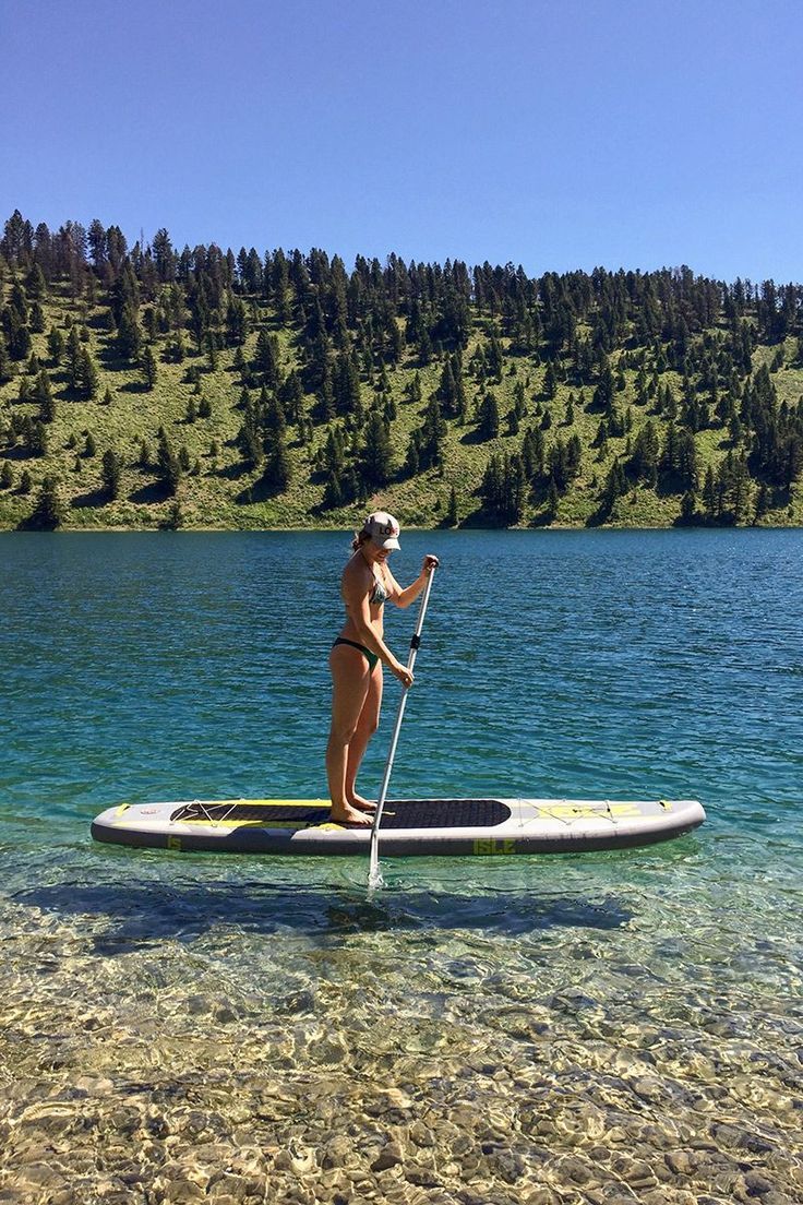 a woman is standing on a paddle board in the water