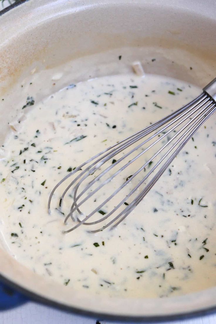 a pot filled with cream sauce and whisk