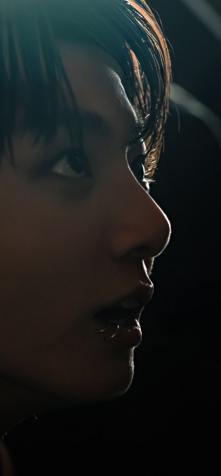 a woman with black hair and piercings on her nose looking off into the distance