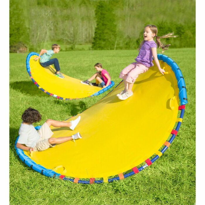 two children playing on an inflatable banana shaped play mat while another child watches