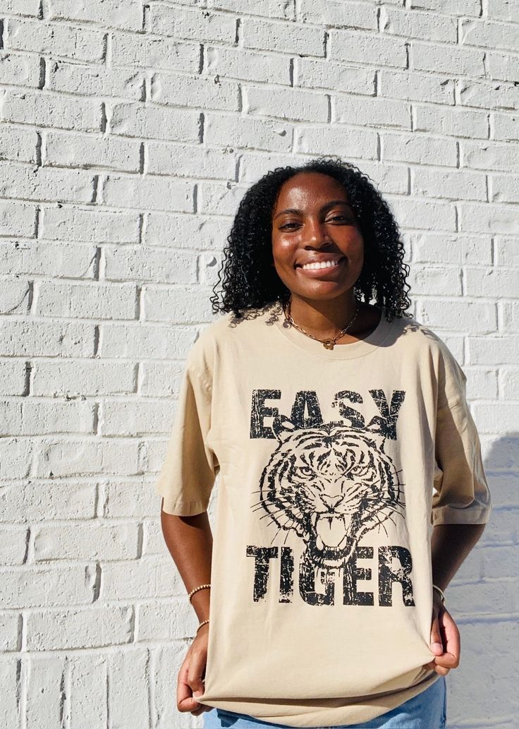 Stay on-trend with the Easy Tiger Oversized Graphic Tee. This tan-colored shirt is designed with a slightly oversized fit, providing both comfort and style. Perfect for any casual occasion, this tee is a must-have for any fashion-forward individual. Spring Oversized Beige T-shirt, Trendy Khaki Crew Neck T-shirt, Oversized Brown T-shirt For Fall, Trendy Brown Relaxed Fit T-shirt, Trendy Beige Relaxed Fit T-shirt, Trendy Beige T-shirt For Streetwear, Trendy Beige Streetwear T-shirt, Casual Beige T-shirt For Day Out, Casual Brown T-shirt With Text Print