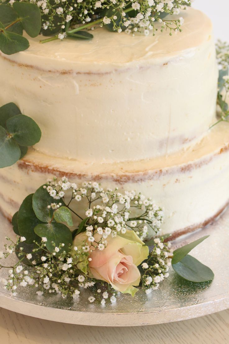 a three tiered cake with flowers and greenery on the top is sitting on a plate