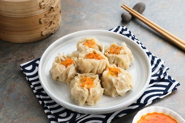 several dumplings on a plate with dipping sauce and chopsticks next to them