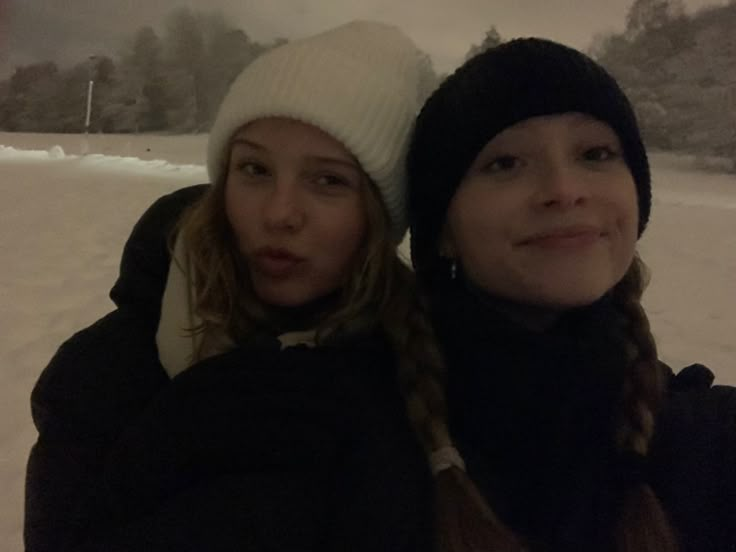 two women standing next to each other in the snow