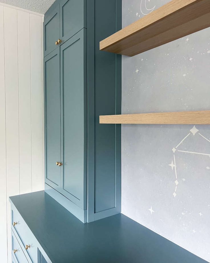 an empty room with blue cabinets and stars painted on the wall behind it, along with shelves