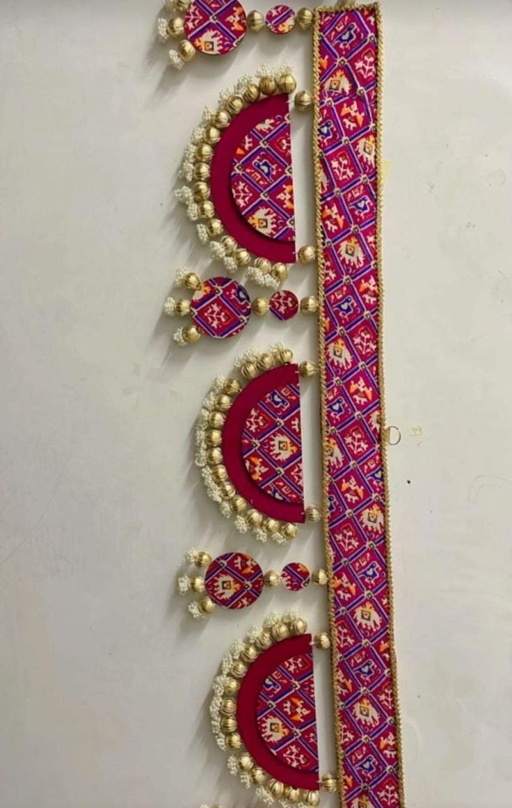 an intricately decorated wall hanging with beads and pearls on it's side, in pink