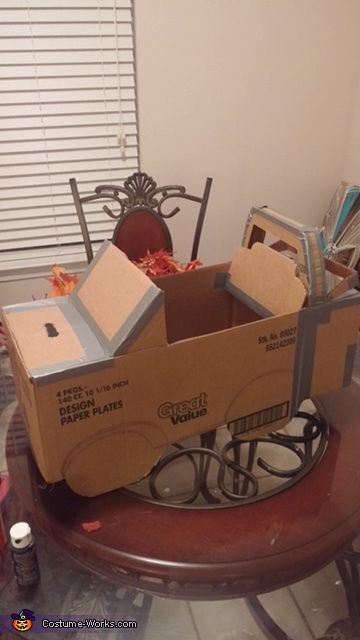 an open cardboard box sitting on top of a table filled with assorted boxes and other items