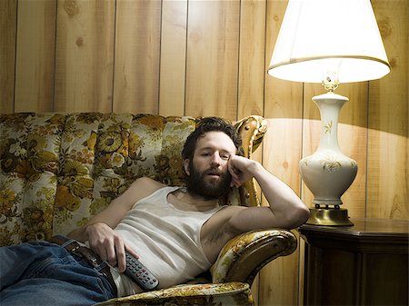 a man sitting in a chair next to a lamp