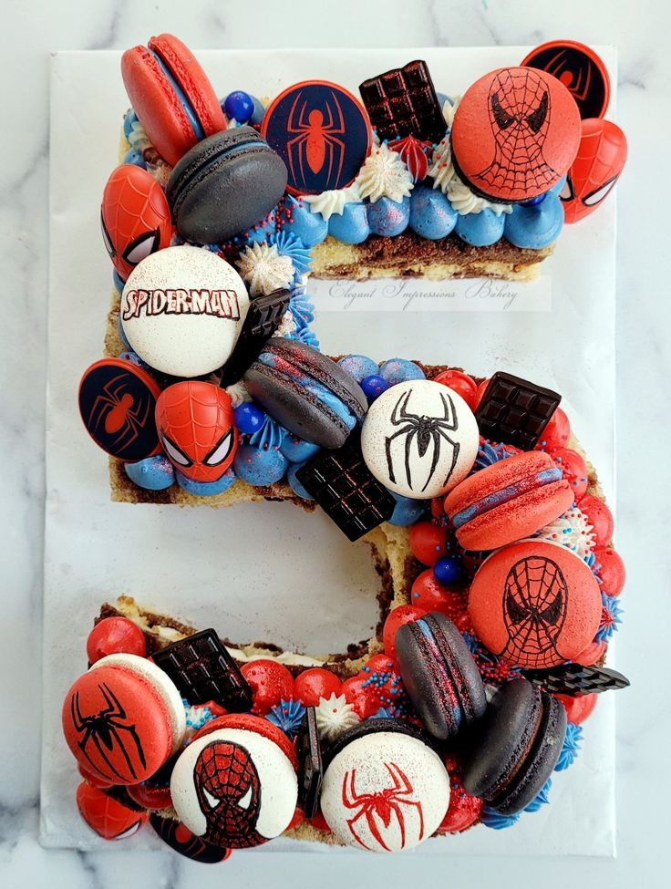 the letter e is made out of cookies and spiderman candies on top of cake