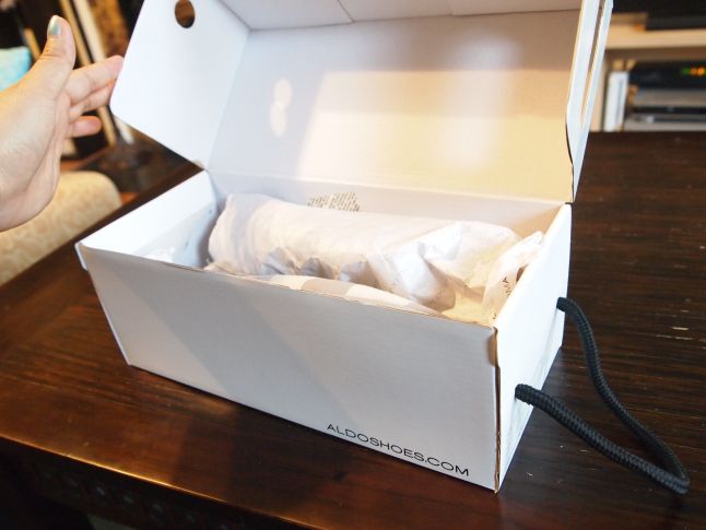 an open white box sitting on top of a wooden table next to a persons hand