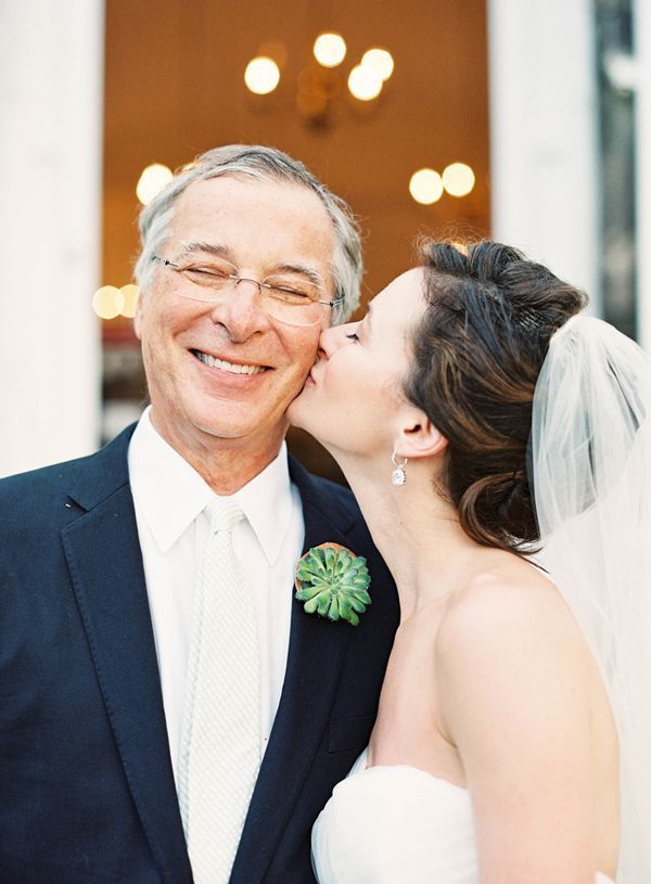 a bride kissing her father on the forehead