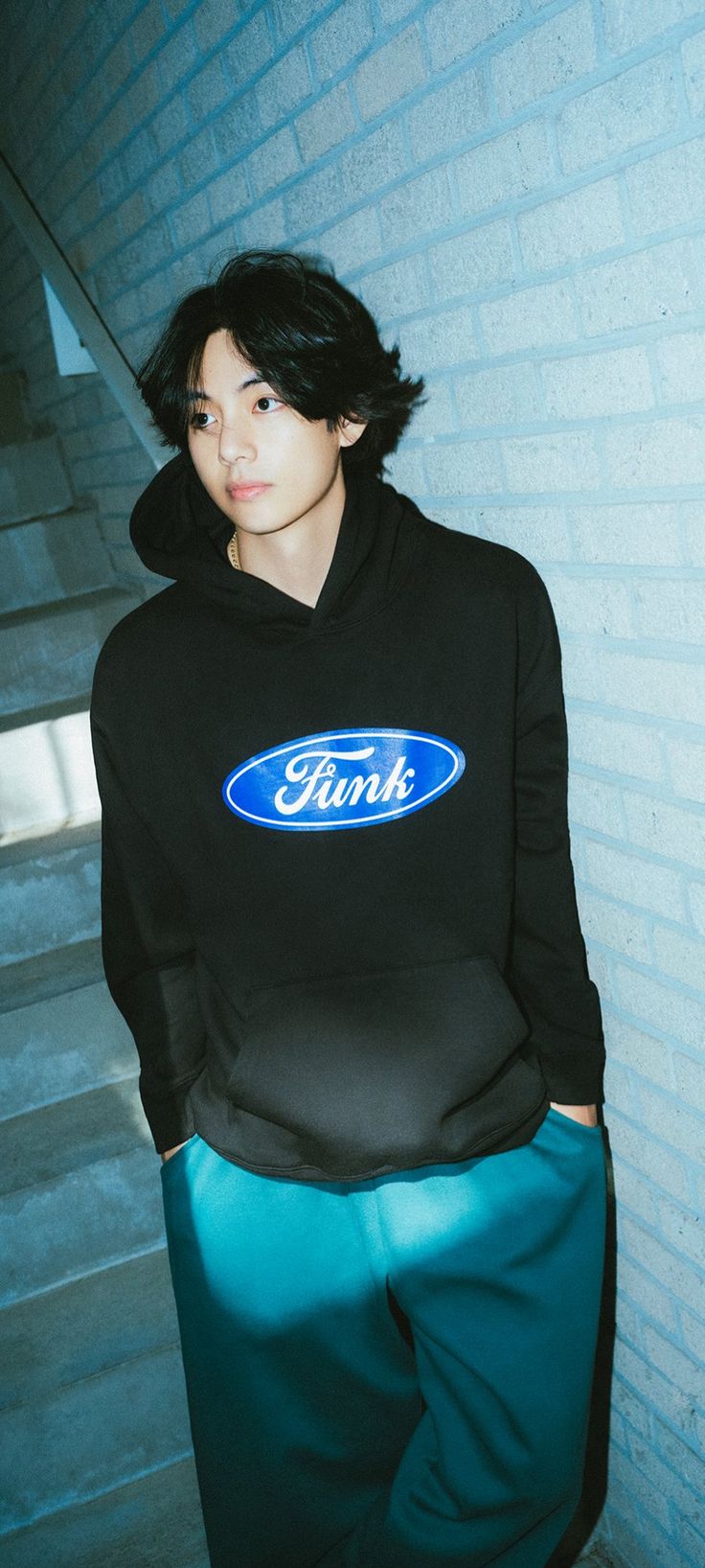 a young man wearing a black hoodie with the ford logo on it, standing in front of some stairs