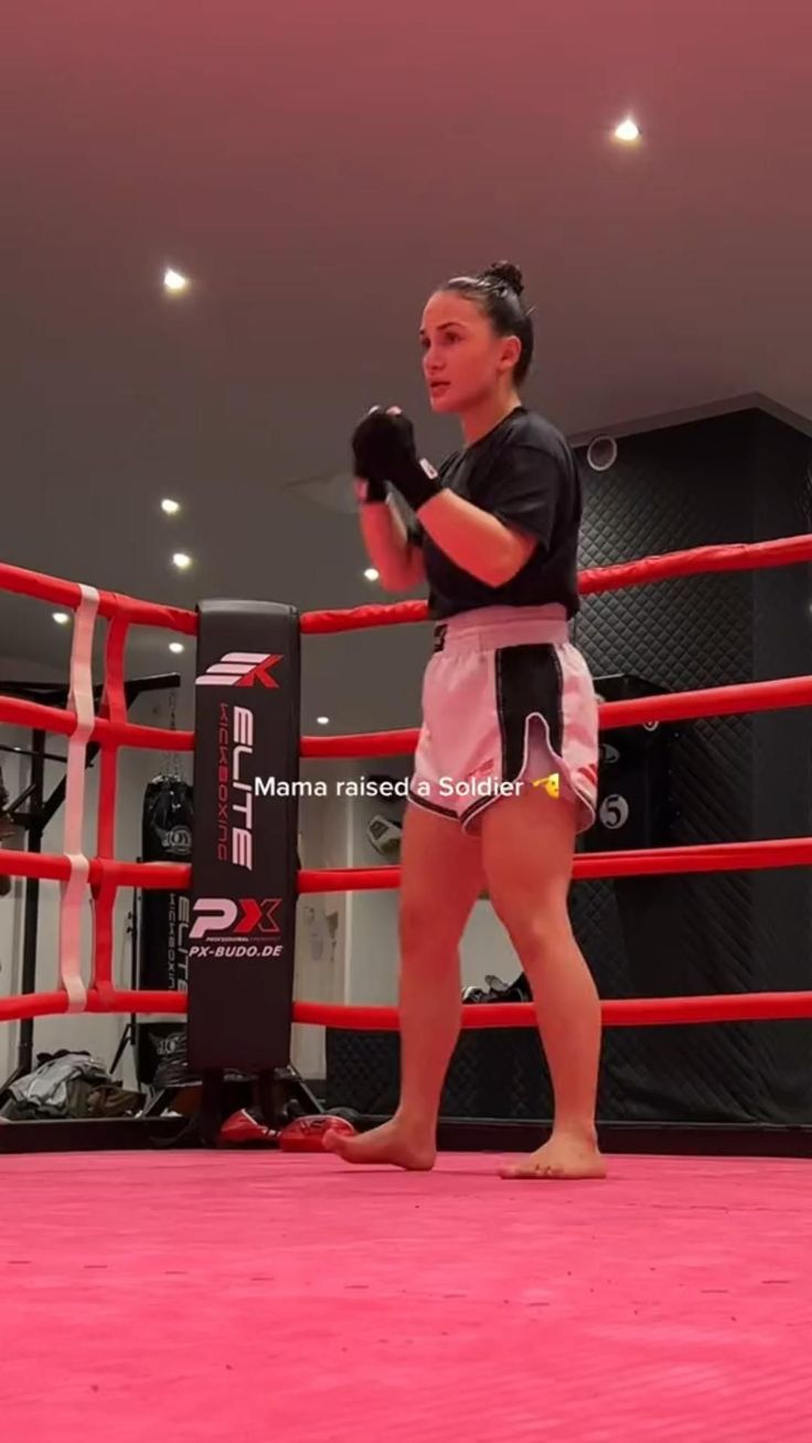 a woman standing in the middle of a boxing ring