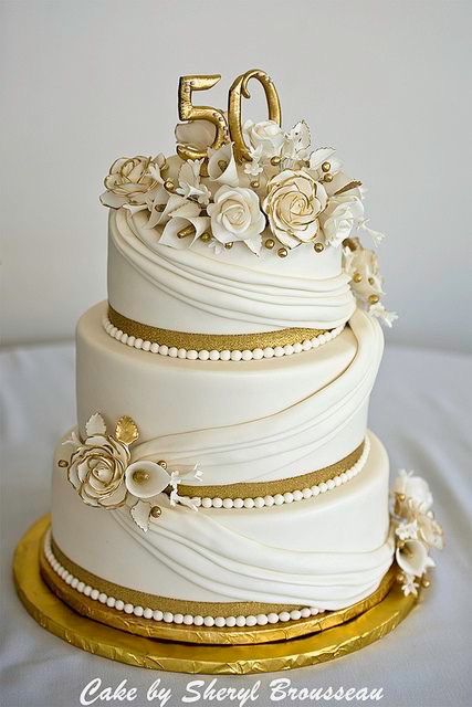 a white wedding cake with flowers and the number 50 on it's top tier