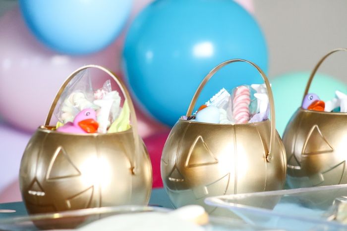 two gold easter baskets filled with candy and marshmallows sitting on a table