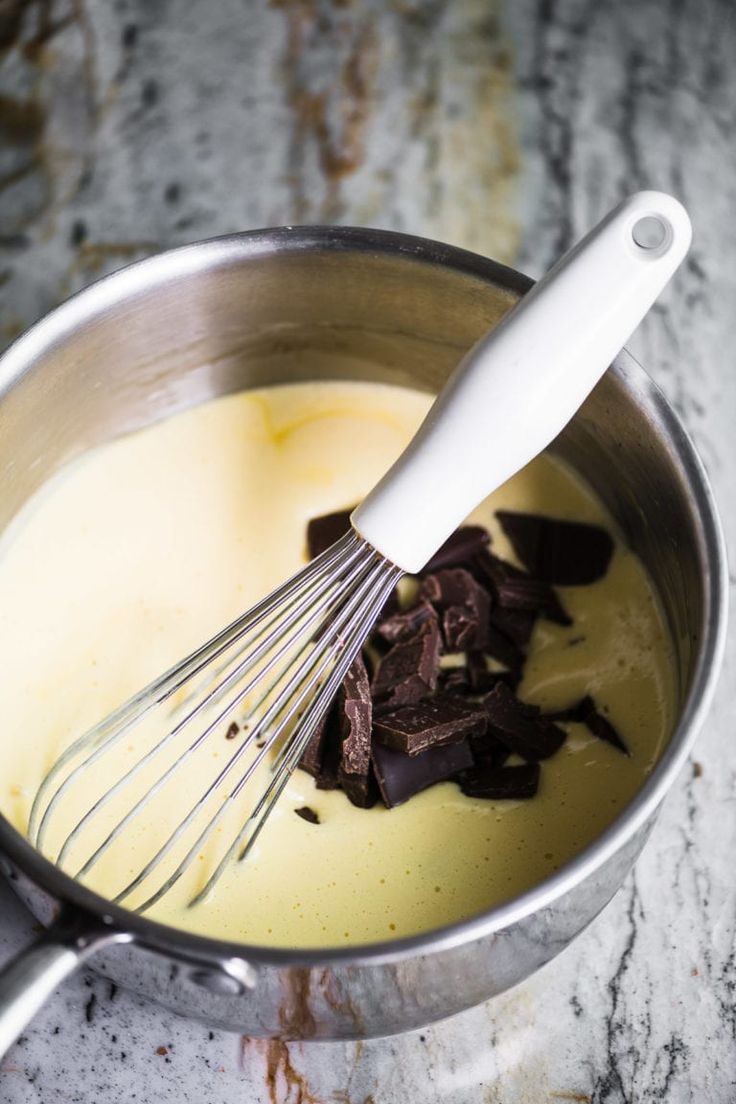 a whisk in a pot filled with pudding and chocolate chips on a marble counter top