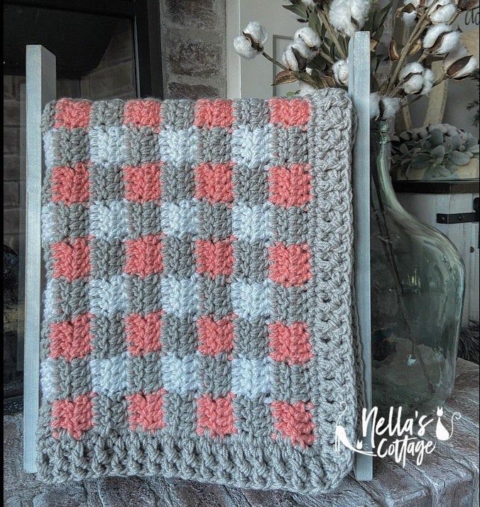 a crocheted blanket sitting on top of a table next to a vase with flowers