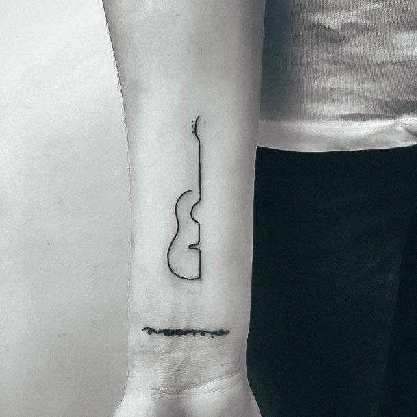 a black and white photo of a guitar tattoo on the left inner arm, with an arrow in the middle