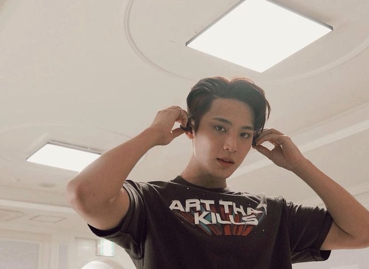 a young man is holding his hair in the air while wearing a t - shirt