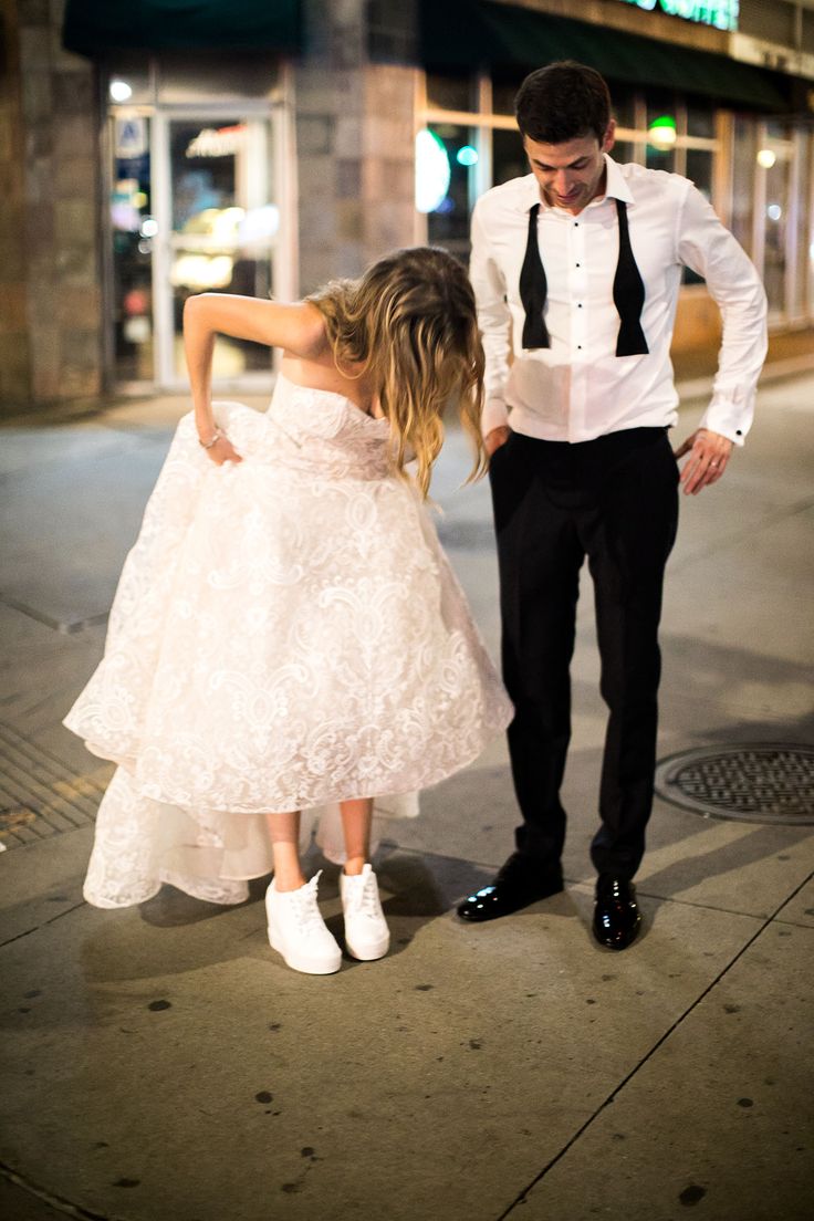 a man and woman in formal wear standing next to each other on the street at night