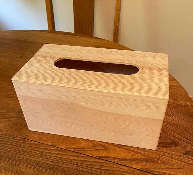 a wooden tissue box sitting on top of a wooden table next to a brown chair