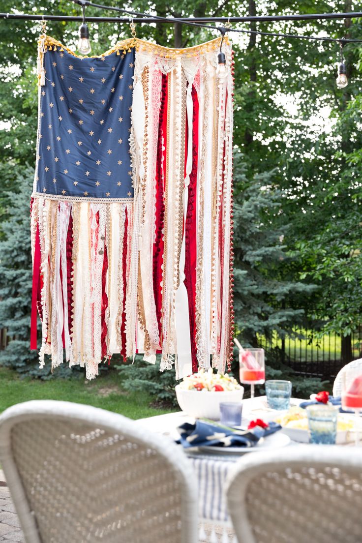 an american flag hanging from a string over a table with chairs and plates on it