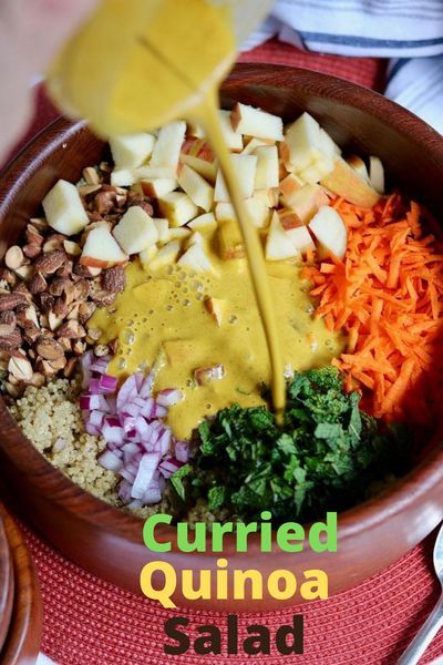 a bowl filled with chopped vegetables and dressing being poured into the mixtures in it