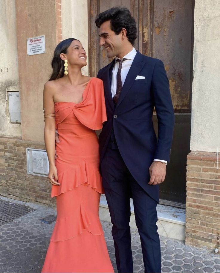 a man and woman standing next to each other in front of a door wearing formal attire