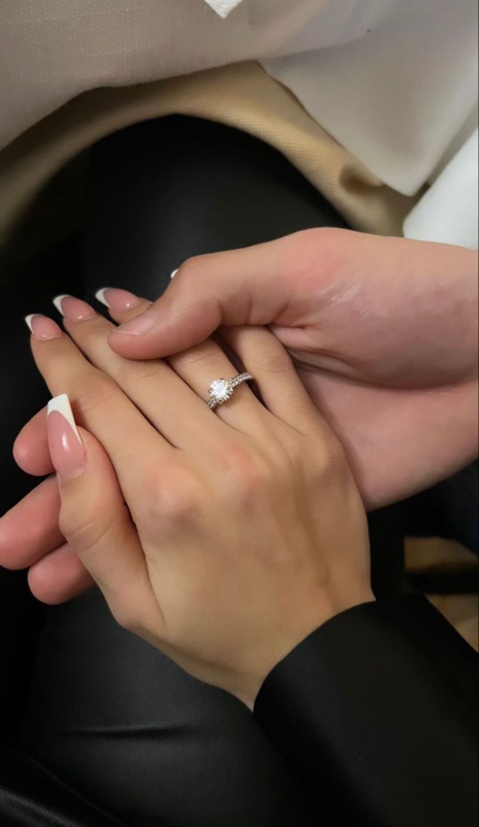 two people holding each other's hands while sitting on a black leather chair with white nail polish