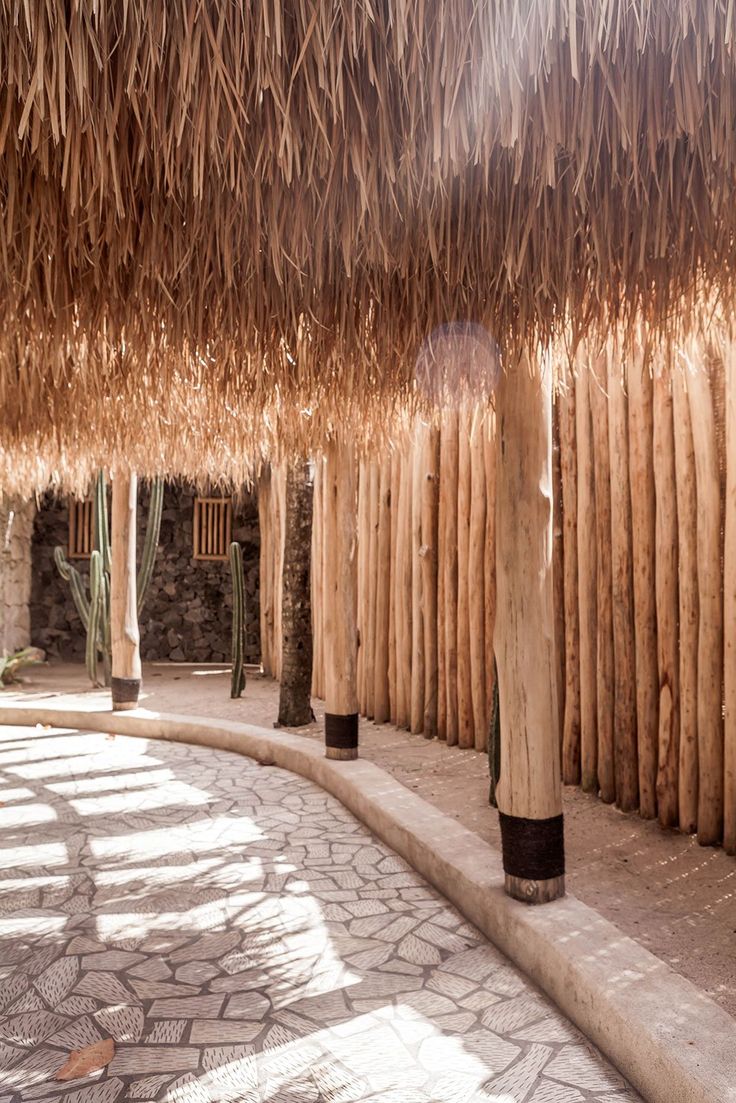 the inside of a hut with straw roof and stone flooring, along with several tall wooden poles