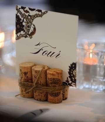 wine cork place card holders on a table with candles in the background at a wedding reception