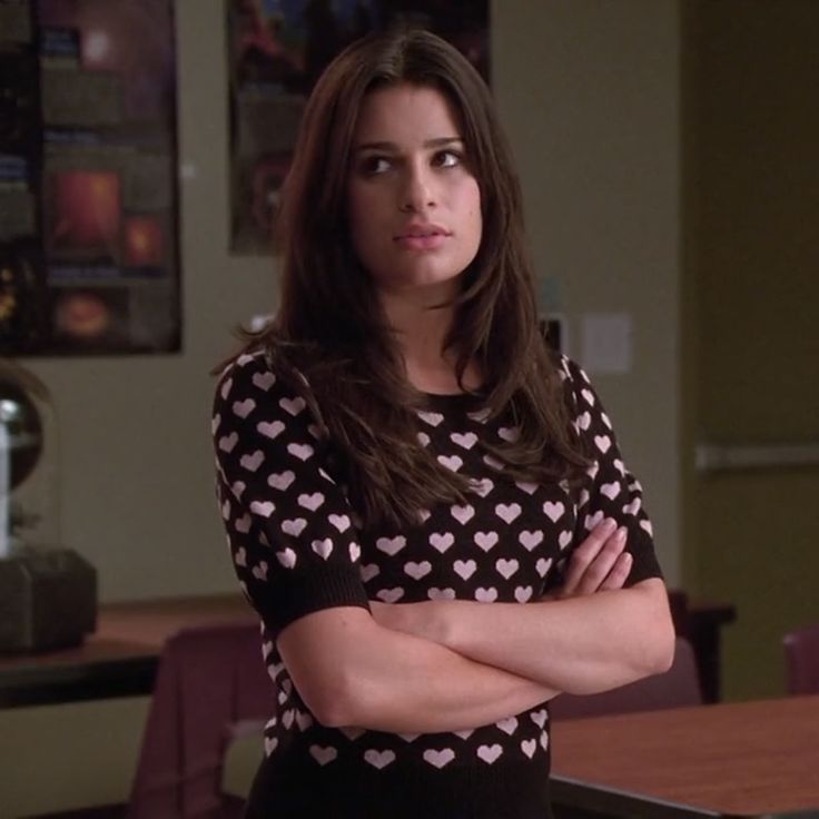 a woman standing in front of a table with her arms crossed