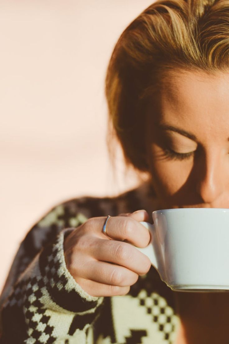 a woman drinking from a white cup with the caption american run on just about any cup of joe they can get their hands on