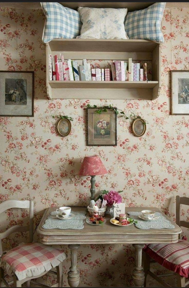 two chairs and a table in a room with floral wallpaper on the walls behind them