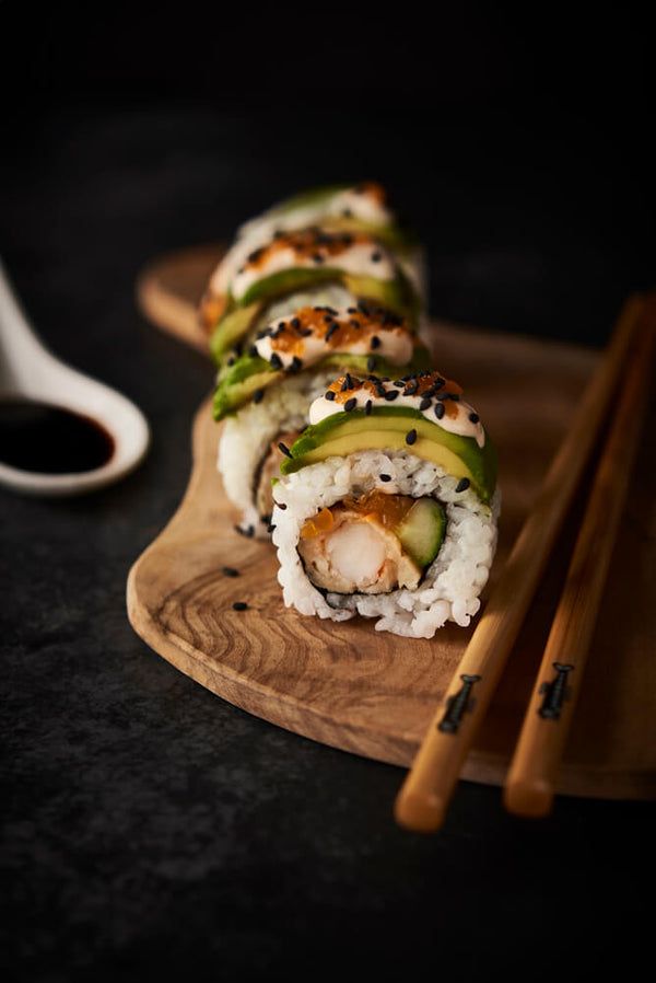 sushi rolls with avocado, cucumber and sesame seeds on a cutting board