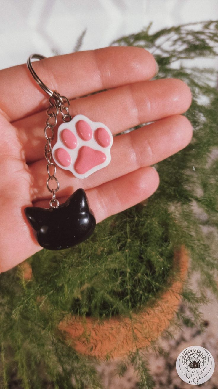 a hand holding a key chain with a cat paw on it