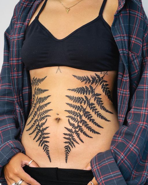 a woman's stomach with a fern tattoo on her belly and the bottom part of her stomach