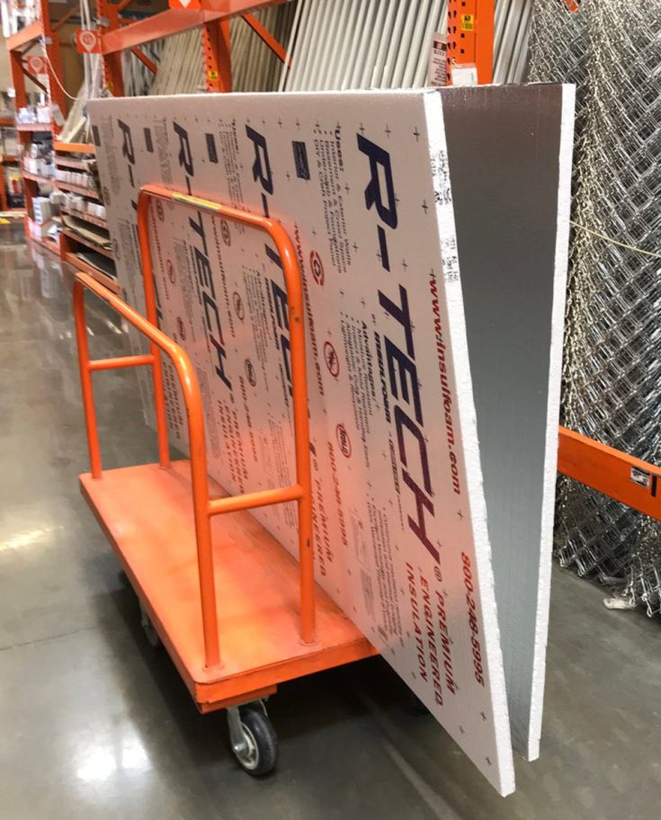 an orange hand truck with a large sign on it's side in a warehouse