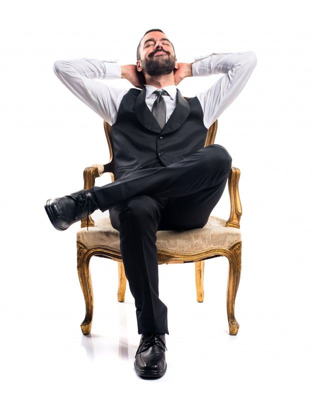 a man in a suit sitting on a chair with his hands behind his head and eyes closed