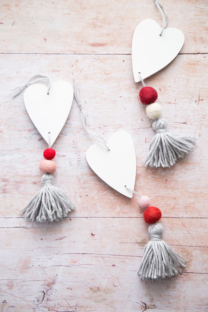 three heart shaped ornaments with tassels and pom - poms hanging from strings