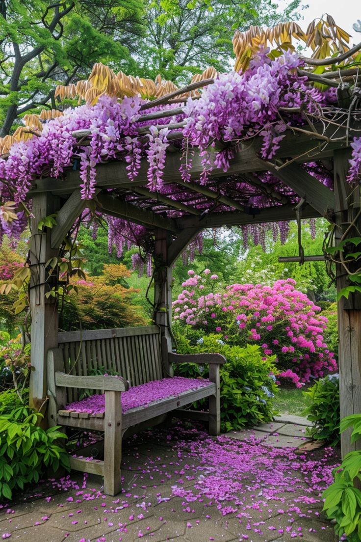 a wooden bench sitting under a purple flower covered arbor