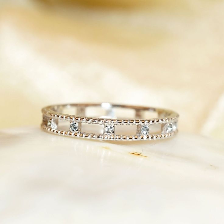 a close up view of a wedding ring on a white marble surface with gold and diamond accents