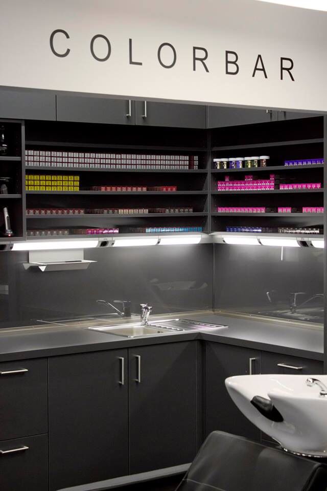 a hair salon with gray cabinets and black counter tops, white sink and mirror on the wall