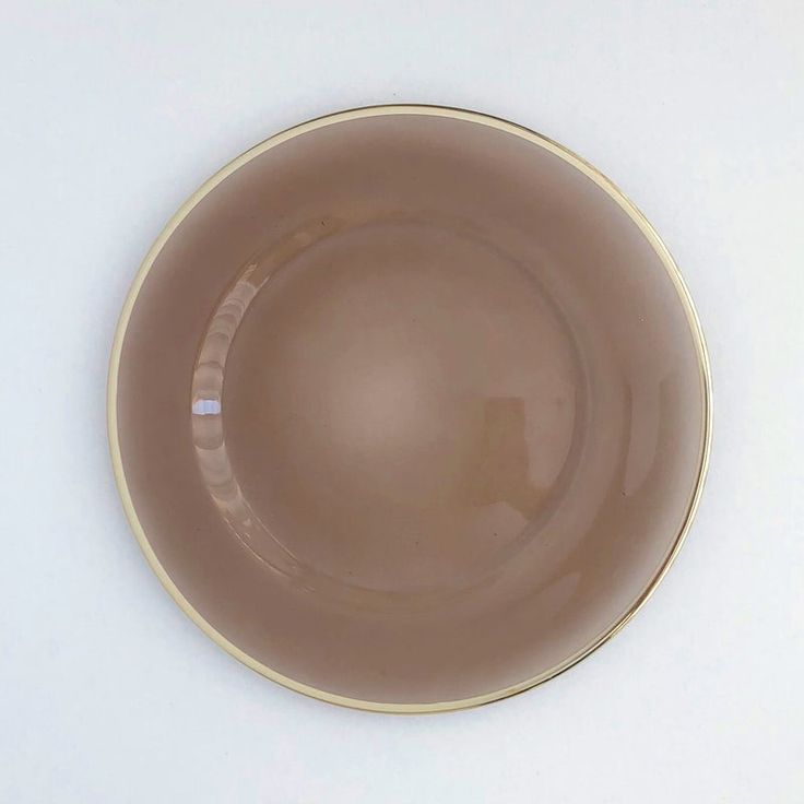 a brown and gold plate on a white surface with an empty bowl in the middle