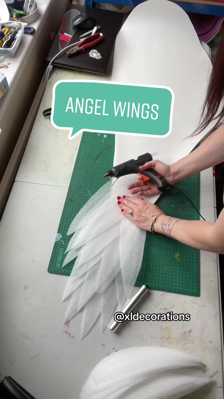 a woman using scissors to cut fabric on a piece of paper with the words angel wings above it