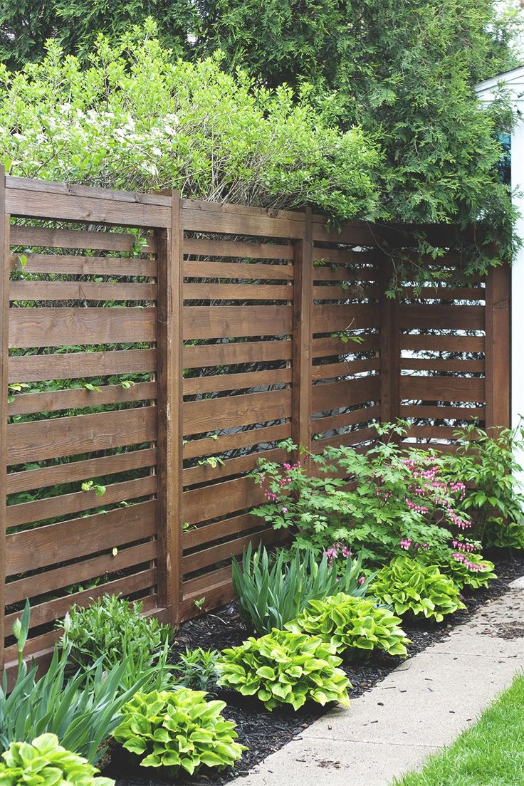 a wooden fence surrounded by plants and flowers