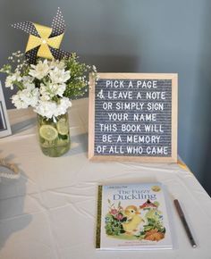 a table topped with a vase filled with flowers next to a sign that reads pick a page leave a note or simply sign your name