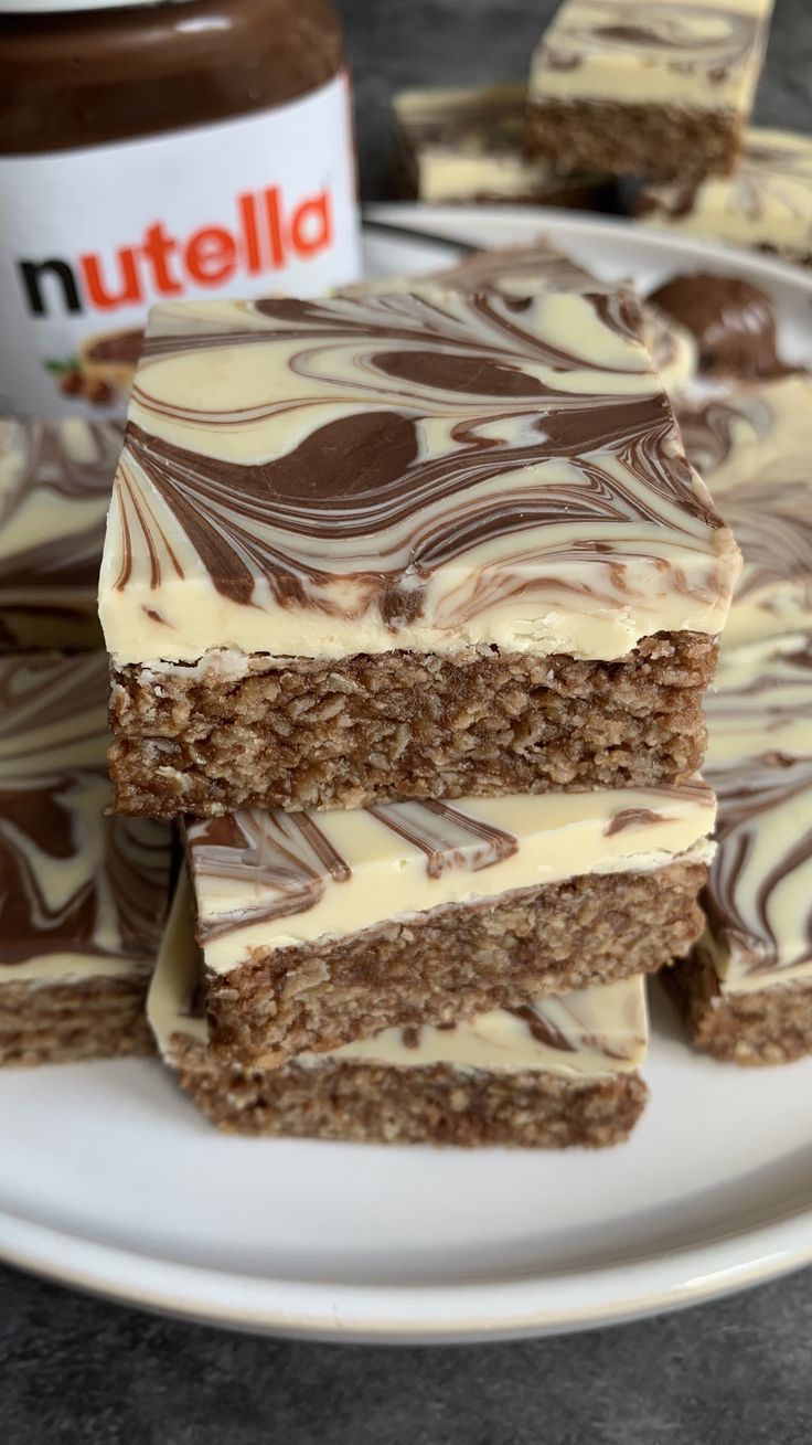 several pieces of cake on a plate with nutella spread around it and peanut butter in the background