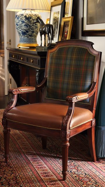 a chair sitting on top of a rug in front of a table with a vase